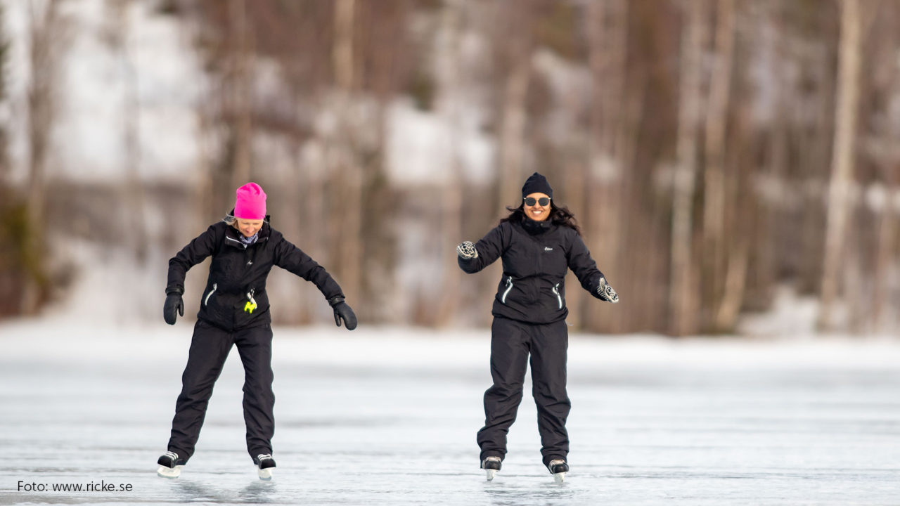 Två kvinnor som åker skridskor på isen.