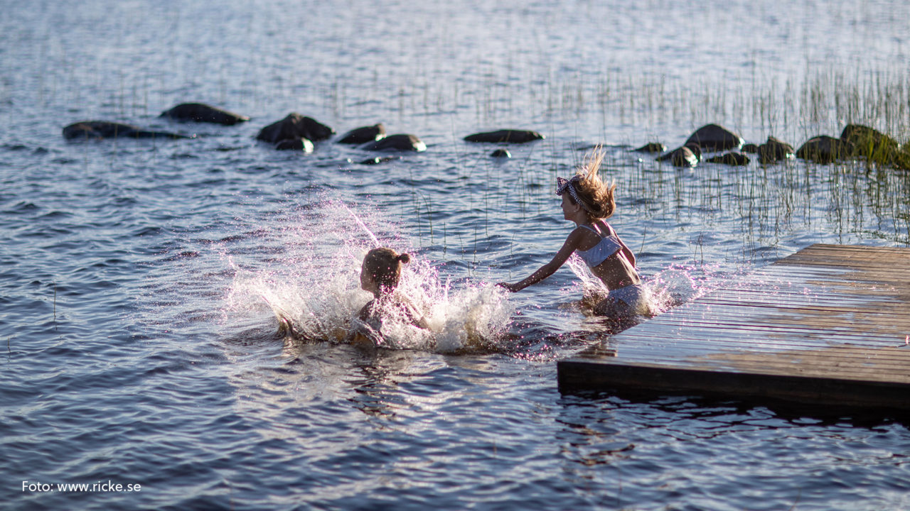 Två barn som hoppar i en sjö.
