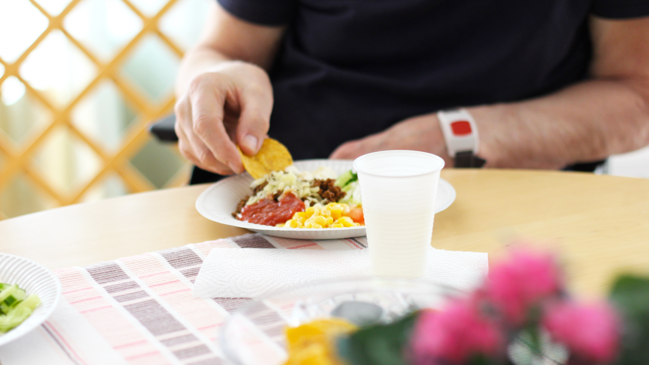 Person som sitter och äter tacos. Endast handen på personen syns.